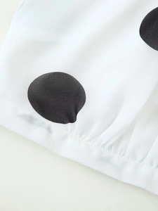 Detailaufnahme von weißem Chiffonstoff mit großen schwarzen Punkten und feinen Plissees