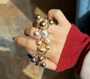 Detalle de anillos ajustables con doble bola de oro y plata en la mano de una modelo