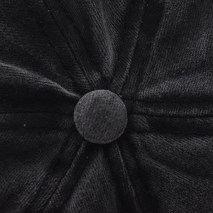 Macro shot of black corduroy baseball cap crown showing fabric button and stitched seams