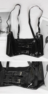 Detail of black glossy corset vest featuring adjustable metal buckles and high-shine finish