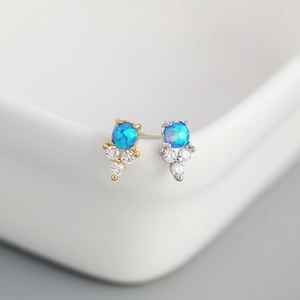 Macro shot of blue opal stud earrings with zirconia accents in gold and silver settings