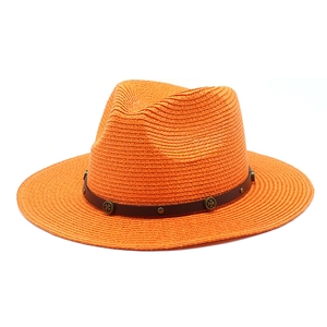 Detail of orange straw jazz hat with brown leather band and bronze cross studs