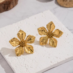 Detail shot of vintage gold flower stud earrings on a textured stone aesthetic pedestal