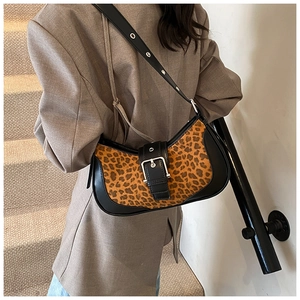 Détail du sac à bandoulière léopard avec boucle argentée porté sur un blazer beige chic