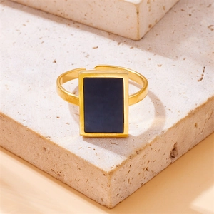 Detail shot of a gold-plated adjustable ring with a black rectangular inlay on beige stone