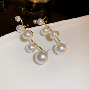 French style gold pearl earrings with gradient size design on a white ceramic plate