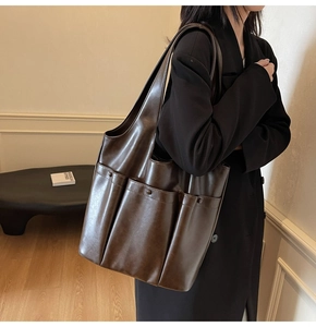 Detail view of a large brown PU leather tote bag with three front pockets for women
