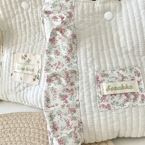 Close-up of quilted cream fabric bag featuring floral ruffles and Sozakka embroidery