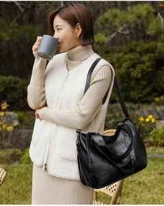 Close-up of black leather tote bag with quilted stitching and wide shoulder strap detail