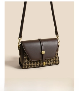 Detail view of the houndstooth fabric and leather stitching on the crossbody bag