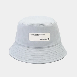 Detail of light blue canvas bucket hat featuring a white fabric label and stitched brim