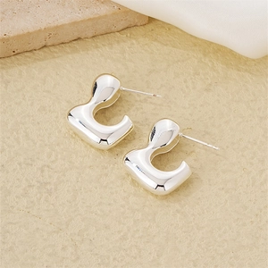 Close-up of silver irregular U-shaped earrings on satin fabric and stone