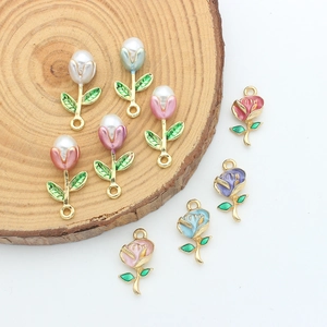 Detail of floral enamel charms and pearl tulips displayed on a natural wood surface