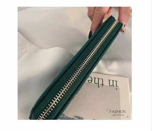 Detail of high-quality gold zipper on dark green textured leather long wallet for women