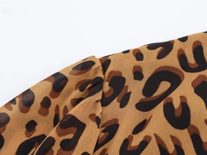 Close-up of leopard print fabric texture and refined pleat details on the dress