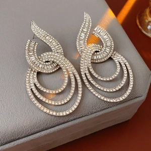 Close-up of geometric silver hoop earrings with clear rhinestones on gray velvet