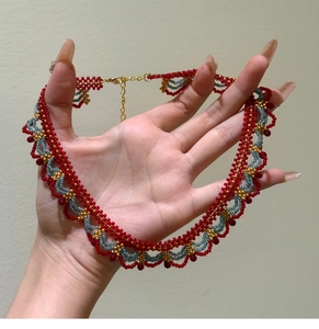 Détail du collier de perles fait main avec perles rouges en gouttes et fermoir doré
