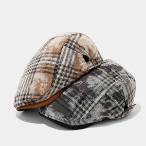 Detail view of plaid newsboy caps with vintage British check patterns and metal buckle