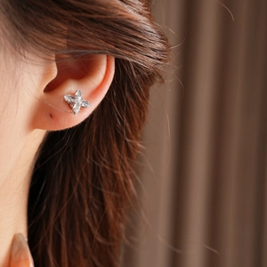 Gros plan d'une boucle d'oreille papillon en zircon argenté portée par un mannequin