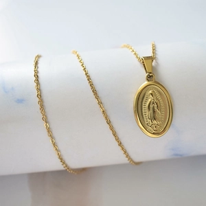 Vue détaillée du collier pendentif ovale Vierge Marie sur un présentoir en marbre blanc