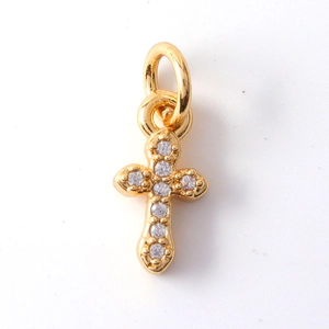 Close-up of a gold cross pendant featuring clear gemstones and a small hanging loop