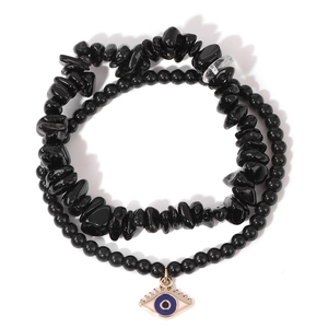 Detail of multi-layer obsidian bracelet featuring irregular stone beads and evil eye pendant