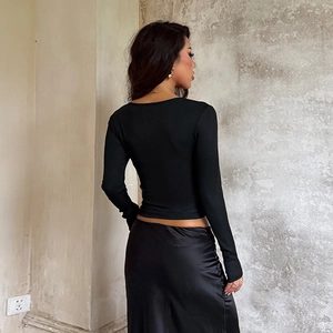 Dettaglio elegante top nero in pizzo a maniche lunghe con gonna in raso di seta