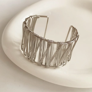 Détail de la texture fil argenté enroulé sur un bracelet ouvert minimaliste en métal