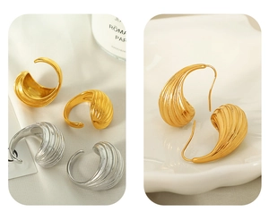 Dettaglio di orecchini cavi placcati oro 18K con trama aerodinamica e design curvo