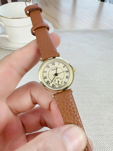 Close-up of a women's vintage roman numeral quartz watch with brown leather strap