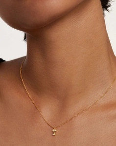 Close-up of gold-plated key necklace featuring rectangular and round zircon gemstones