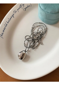 Dual-layer necklace with black cord and silver bean pendant on a white ceramic tray