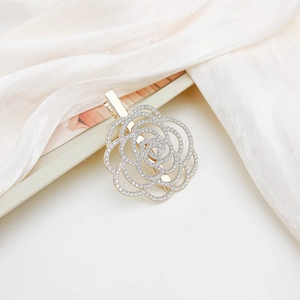 Macro detail of golden metal flower hair clip with sparkling rhinestones on pink silk
