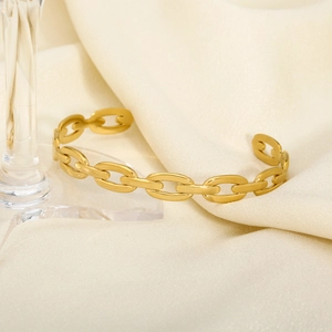 Detailed view of polished gold chain link cuff bangle on soft silk fabric