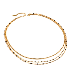 Layered gold stainless steel necklace with black beads on a minimalist white background