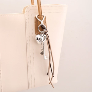 Charm de sac créatif en cuir tressé avec cœur et clé sur un sac à main beige chic