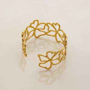 Macro detail of 18K gold plated hollow floral pattern open bangle with clear reflection