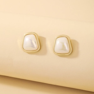 Macro view of geometric trapezoid earrings with gold borders and pearl-like inlay