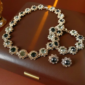 Detail of vintage flower jewelry set with green crystals and gold finish in a brown box