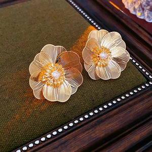 Detail of gold-plated hollow flower stud earring with central cubic zirconia crystal