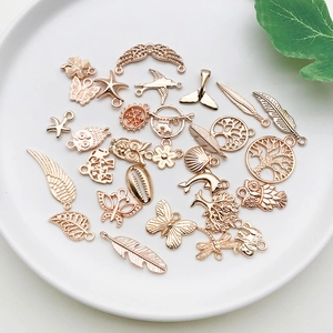 Detail of rose gold DIY jewelry charms including butterfly, feathers and seashells on ceramic