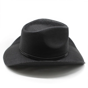Detail of black straw cowboy hat with belt trim and curved brim on white background