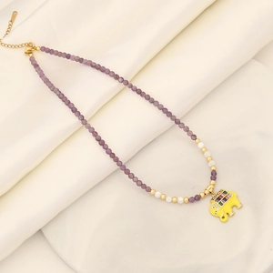 Detail of beaded necklace with purple stones and a gold elephant pendant with colored gems