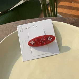 Close-up of red acetate butterfly hair clip with rhinestones on a display card