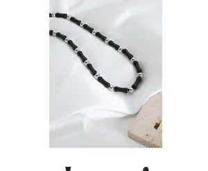 Detail of handmade black agate beaded necklace with silver beads on white silk fabric