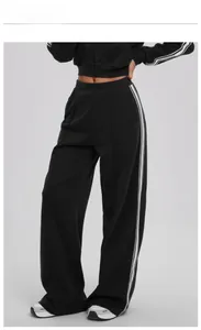 Detail of wide-leg sweatpants featuring double side stripes and relaxed cotton fit