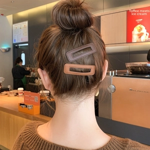 Detail of premium brown faux leather hair clips with stitching on a messy bun hairstyle
