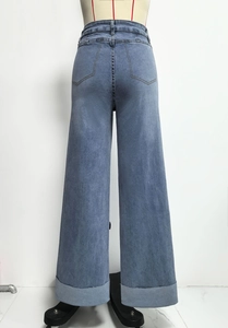 Detailweergave van de lichtblauwe jeans met hoge taille, brede pijpen en grote omslagen
