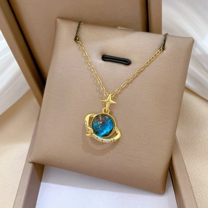 Detailed shot of celestial planet necklace with blue teal stone in a beige jewelry box
