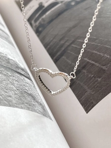 Macro detail of silver heart-shaped pendant with pavé cubic zirconia and O-chain